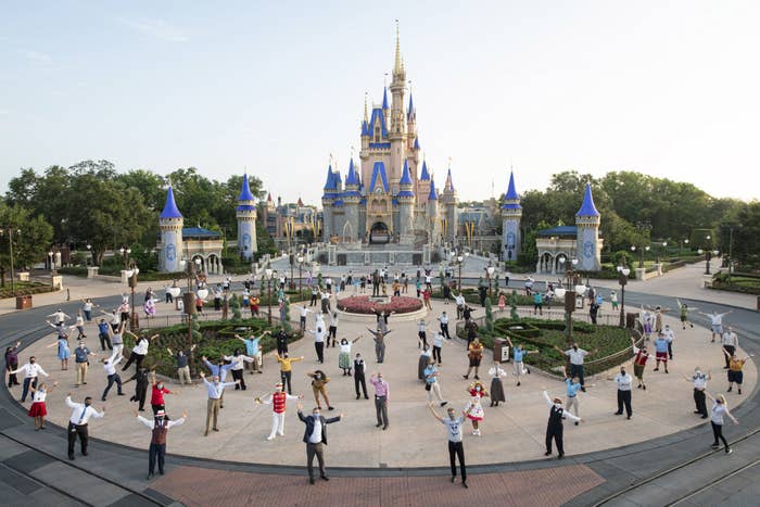 Disney World employees pose while socially distanced outside Cinderella&#x27;s Castle