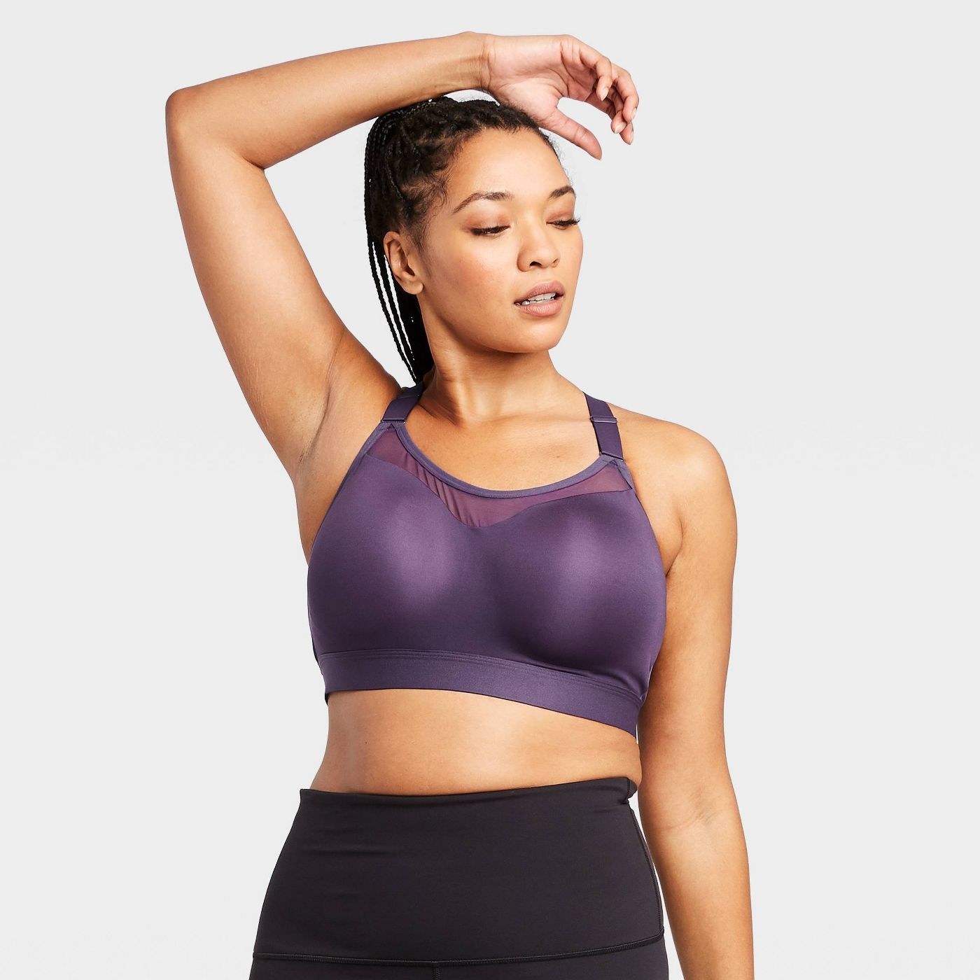 Model wearing the sports bra in purple  with a mesh panel across the top and adjustable straps