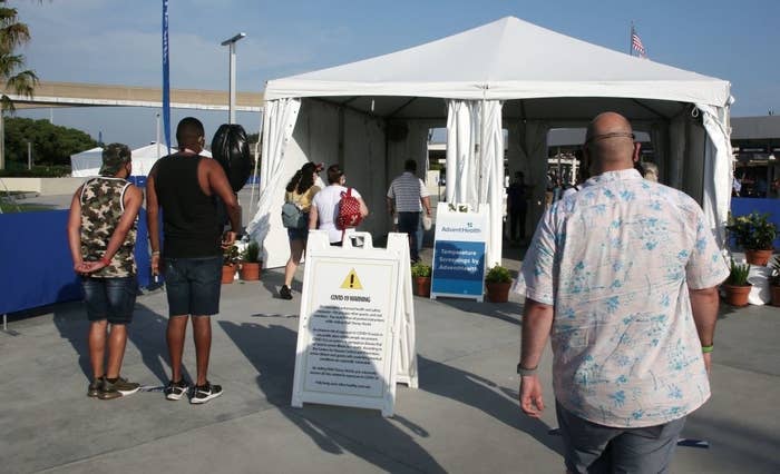 Visitors walk toward a tent to get their temperatures checked before entering the park