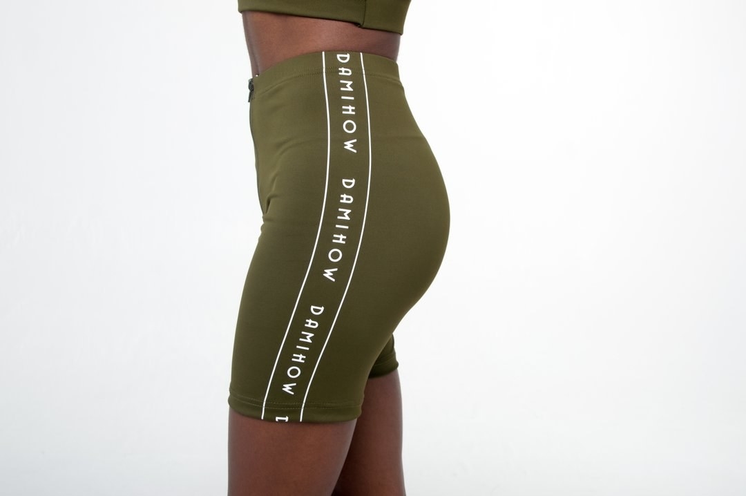 The high-waisted biker shorts in green  with a white stripe down the side with &quot;Damihow&quot; written three times