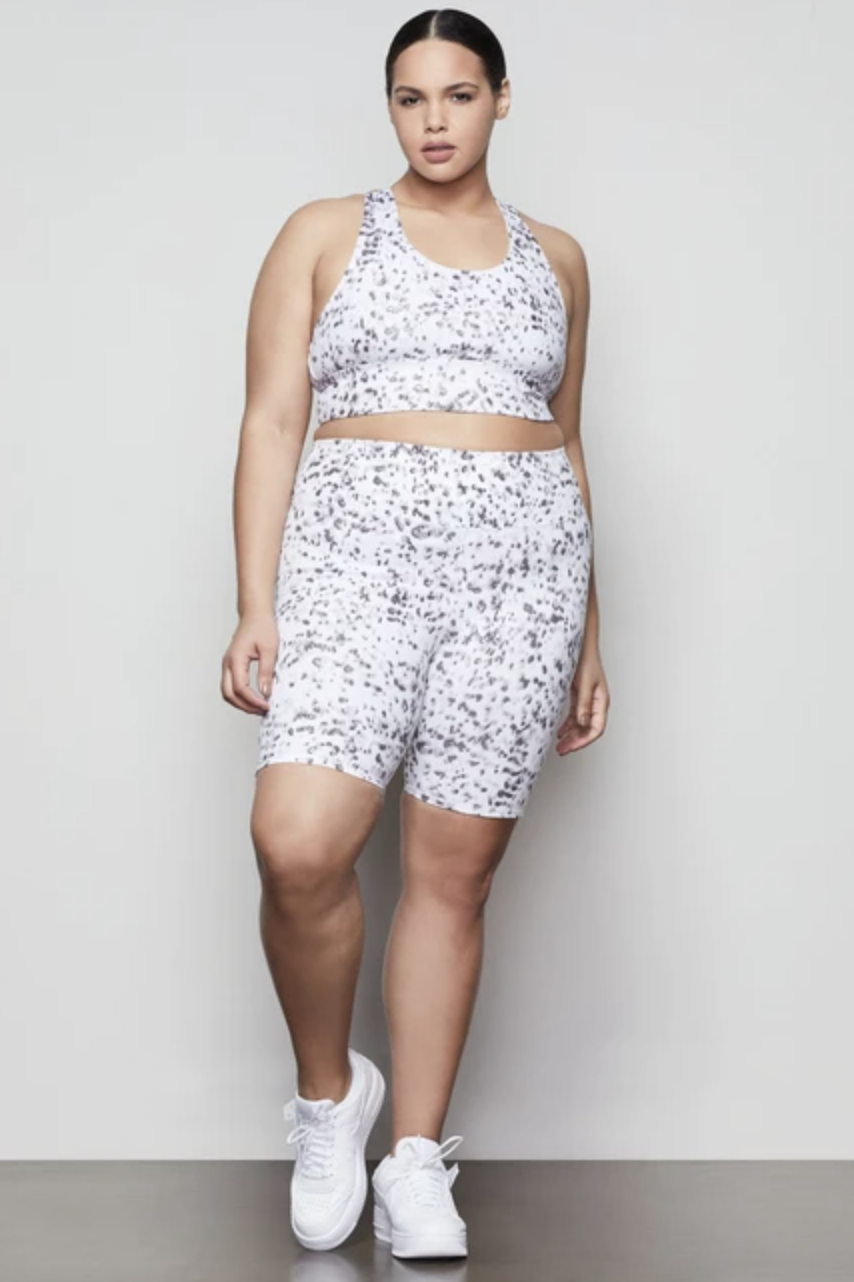 Model wearing the high-waisted bike shorts in white with a black leopard pattern all over them 