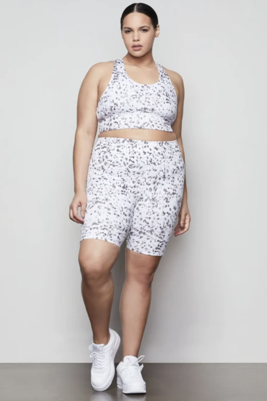 Model wearing the high-waisted bike shorts in white with a black leopard pattern all over them