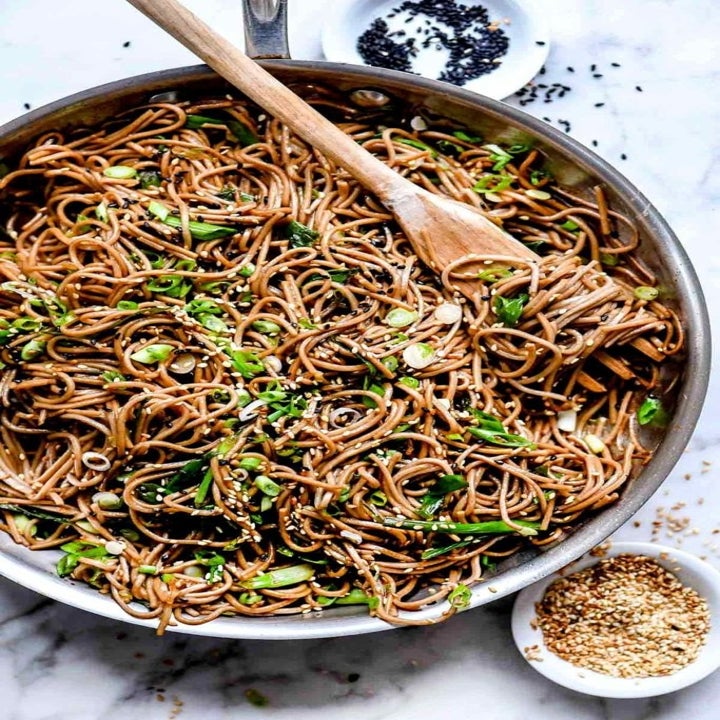 A pan full of sesame soba noodles with scallions.