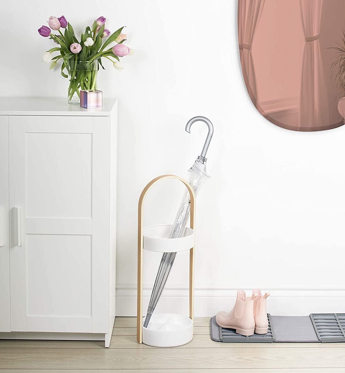 The umbrella stand in a neatly arranged entryway with a clear umbrella inside
