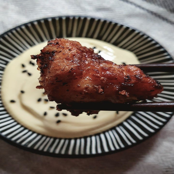 Chopsticks holding a piece of Japanese fried chicken over a bowl of mayo dipping sauce.