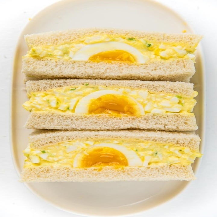 A sliced Japanese egg salad sandwich with soft boiled eggs on the inside.