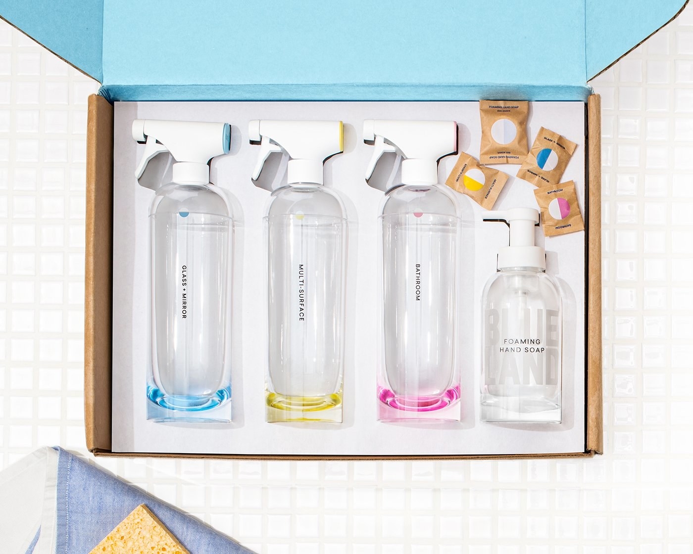 a box with four large glass spray bottles and one smaller spray bottle for hand soap
