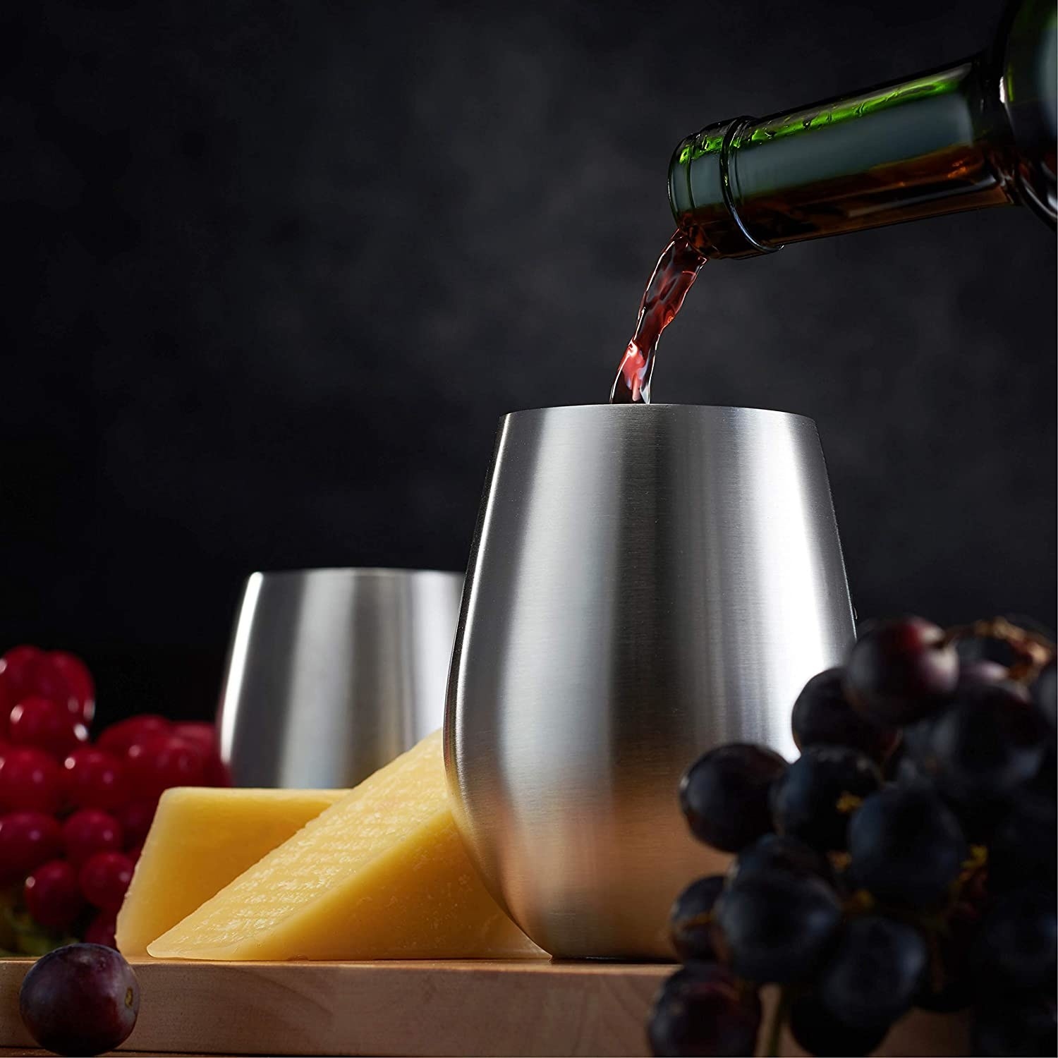 A close up photo of red wine being poured into the stainless steel wine glasses