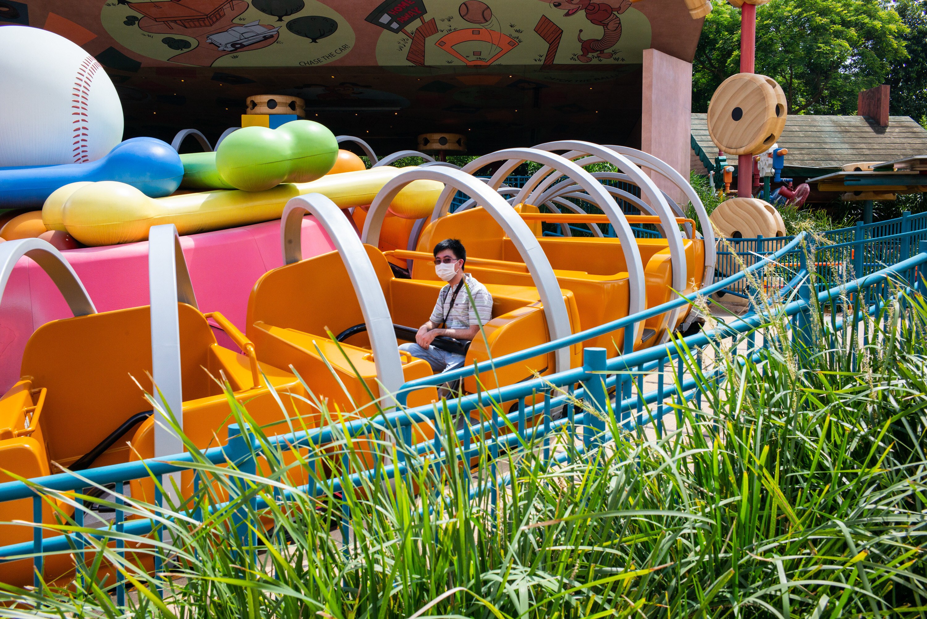 A lone visitor wearing a mask sits on a ride