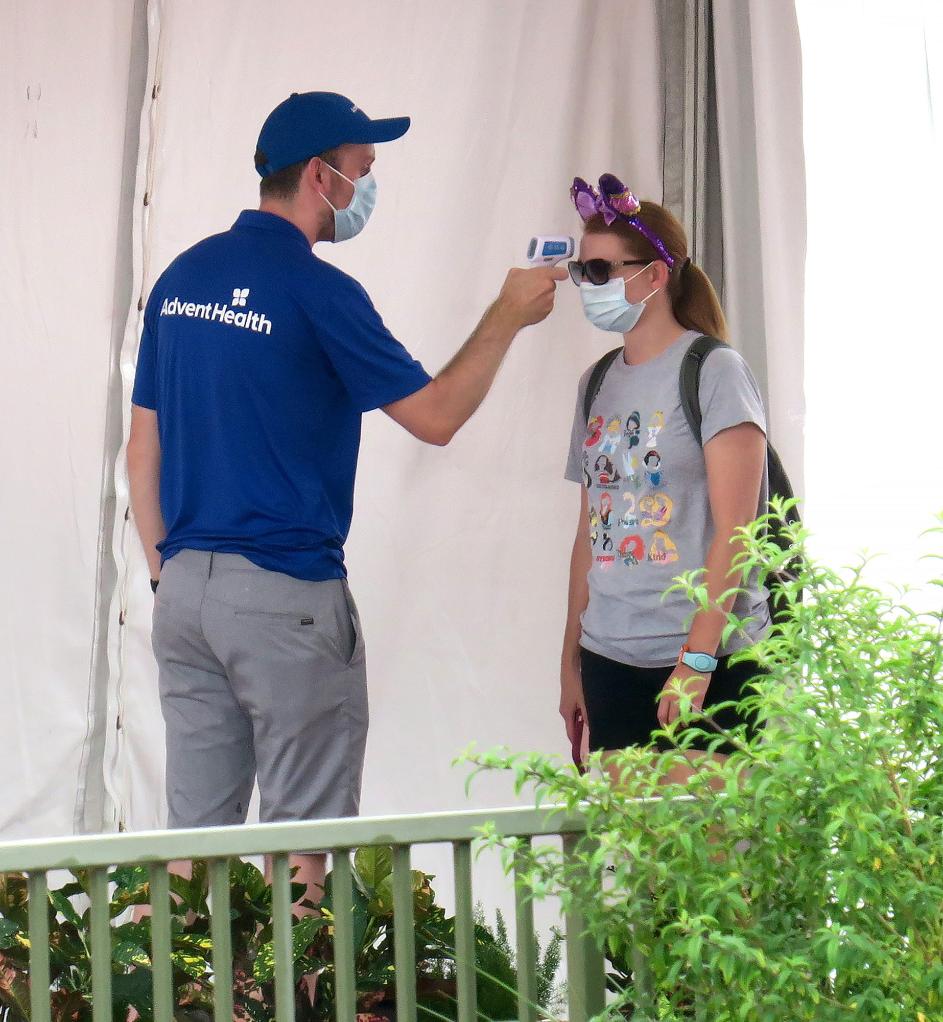 A visitor gets their temperature checked by an employee