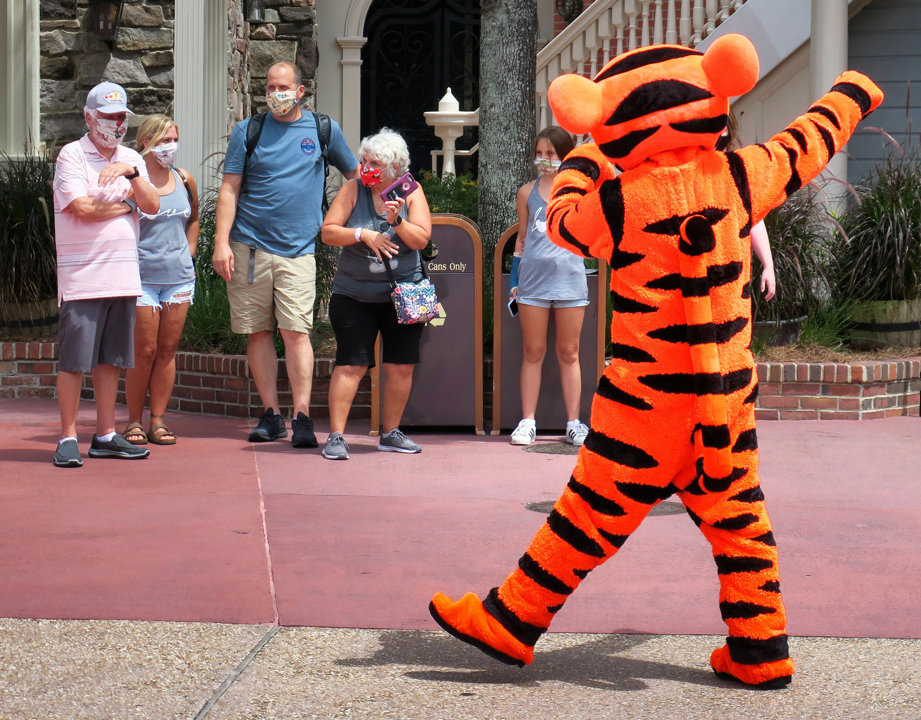 A family wearing masks watches Tigger walk by