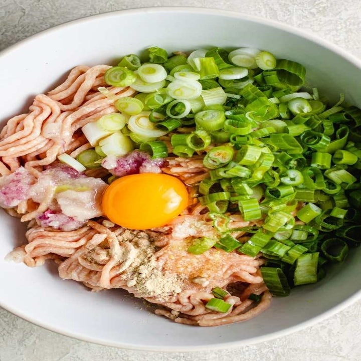 Meatball ingredients including ground chicken, egg, and scallion in a bowl.