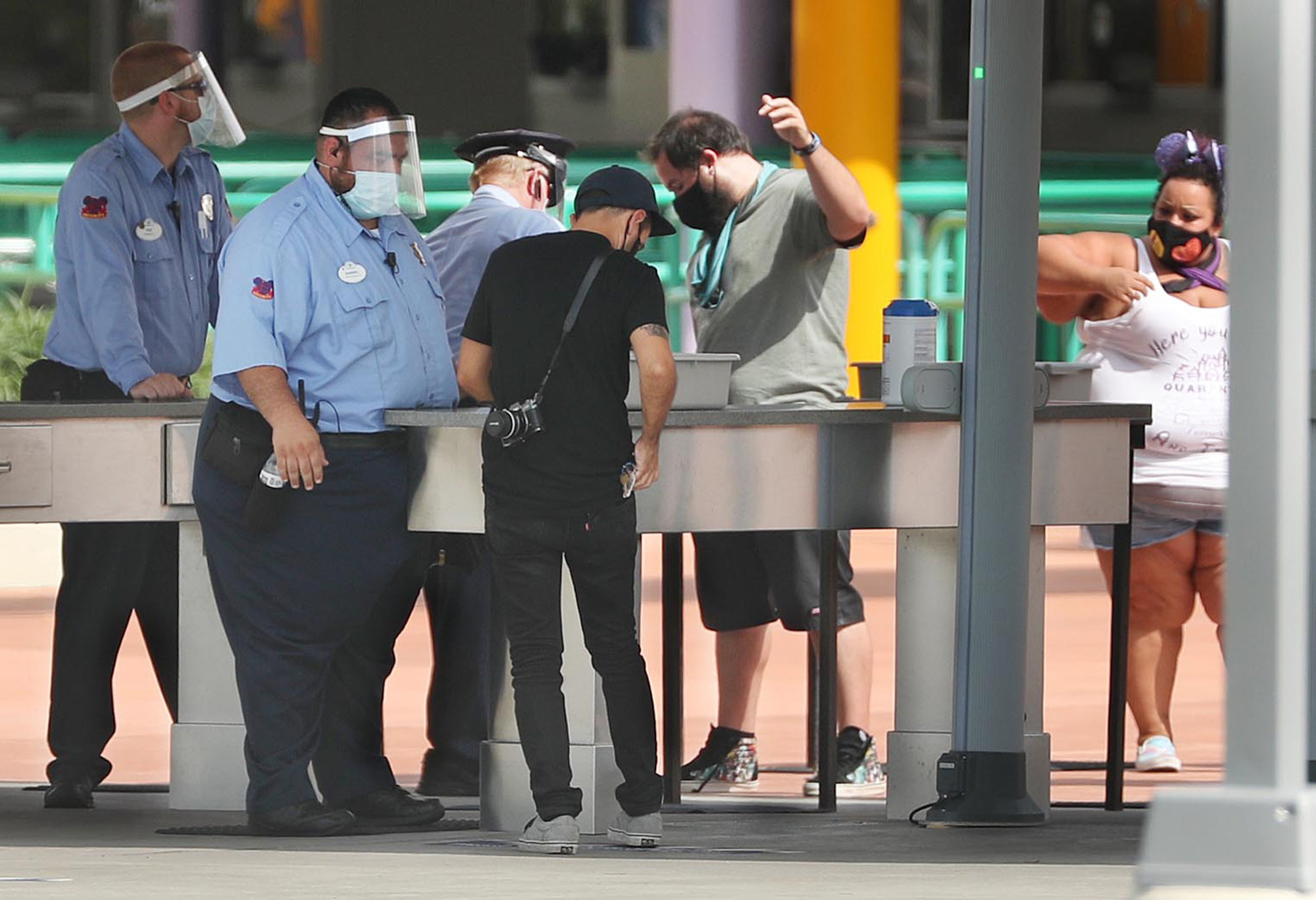 Security guards in face shield check visitors&#x27; bags