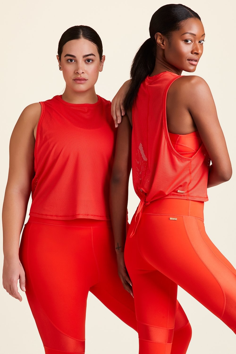 Two models wearing the tank in red with a high neckline and a tie in the back