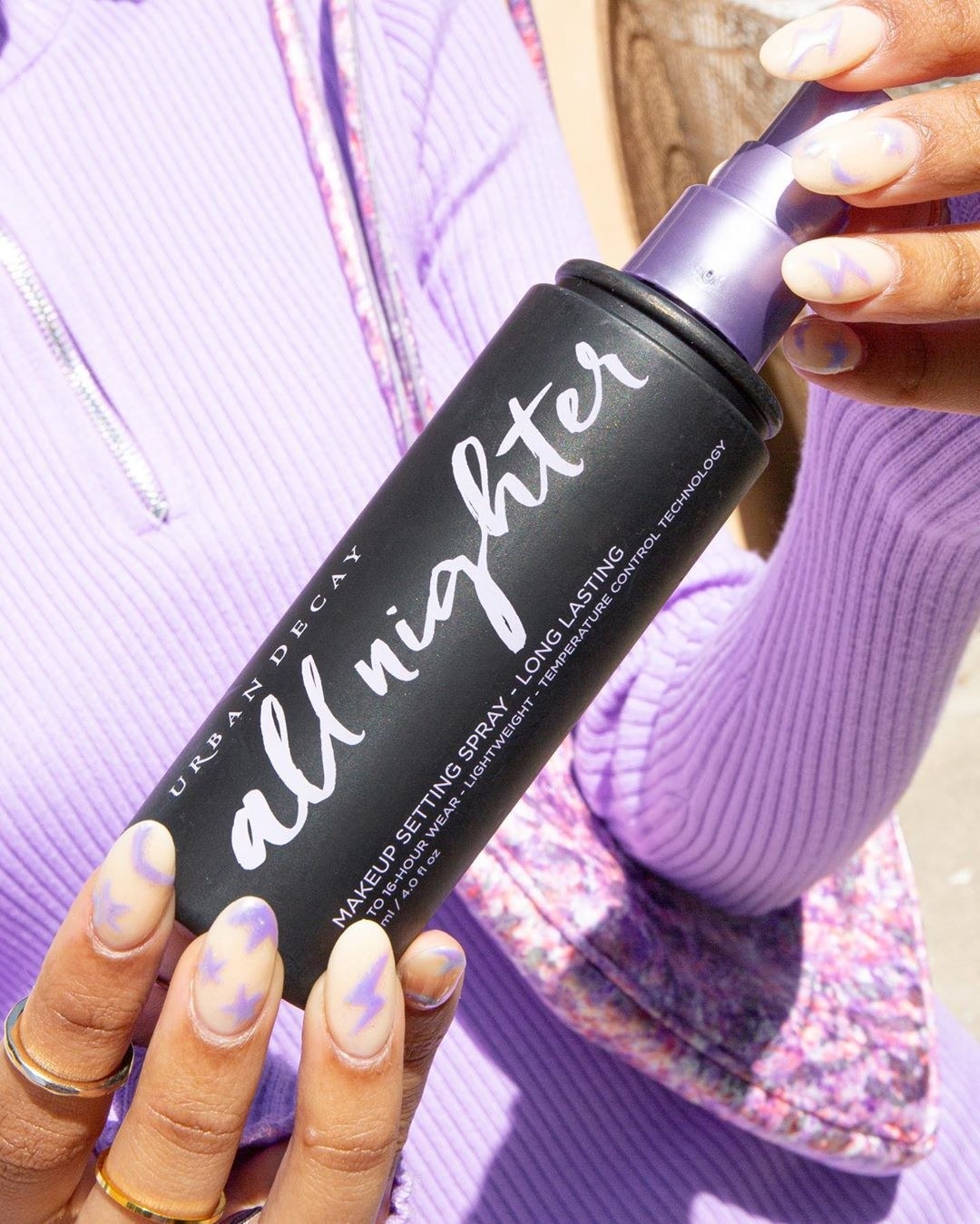 A model holds the Urban Decay All Nighter long-lasting setting spray in their hands