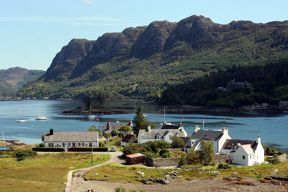 The small village of Plockton is in the forefront, with the Lock Carron behind as well as some tree covered mountains