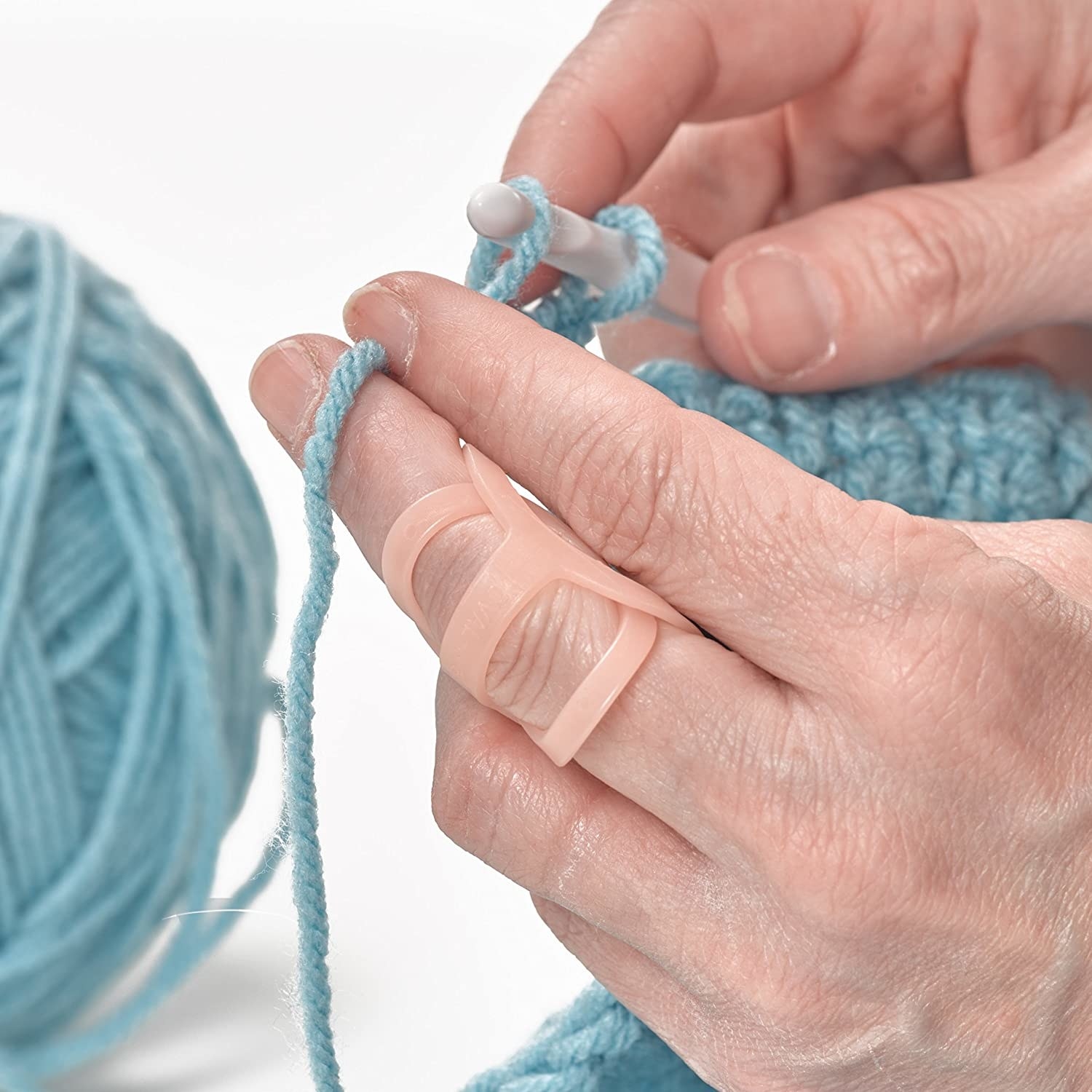 person knitting with the loop-shaped support over a knuckle