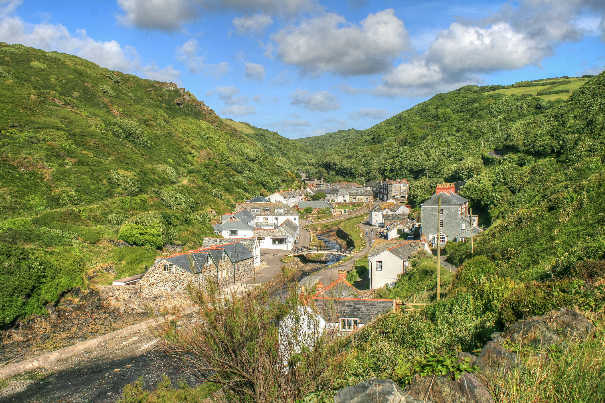 A view from above over the stone houses of the village as it sits in a valley with a river running through 