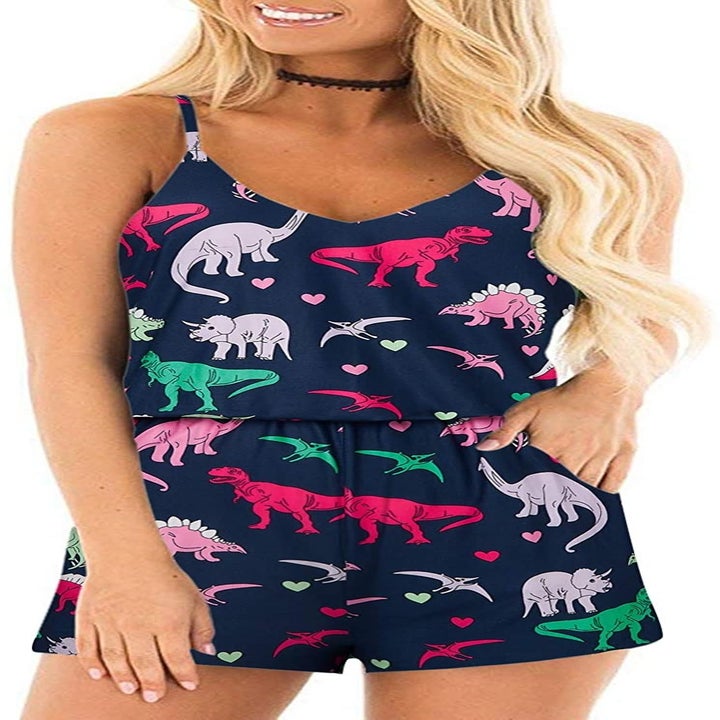 A model wearing the romper in navy with a dinosaurs and hearts print