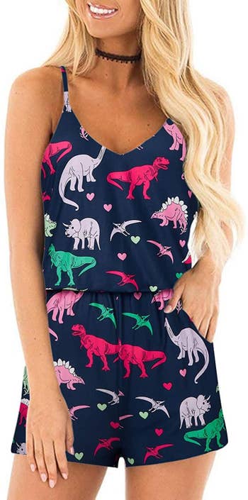 A model wearing the romper in navy with a colorful dinosaurs and hearts print