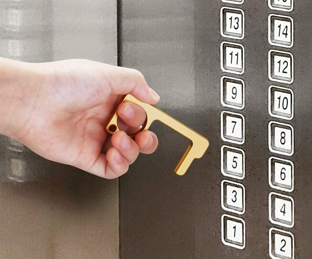 A person holding the tool while getting ready to push an elevator button