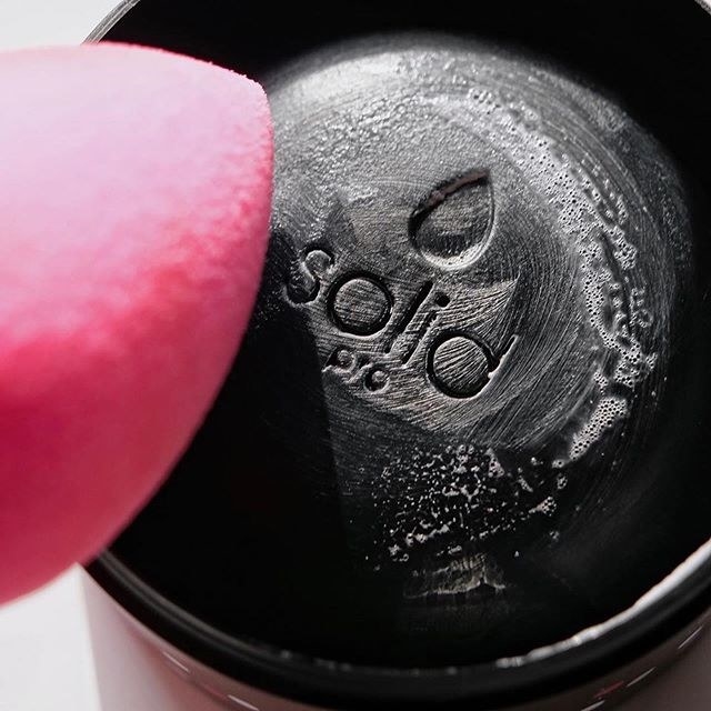Beautyblender sponge being cleaned on charcoal cleaner