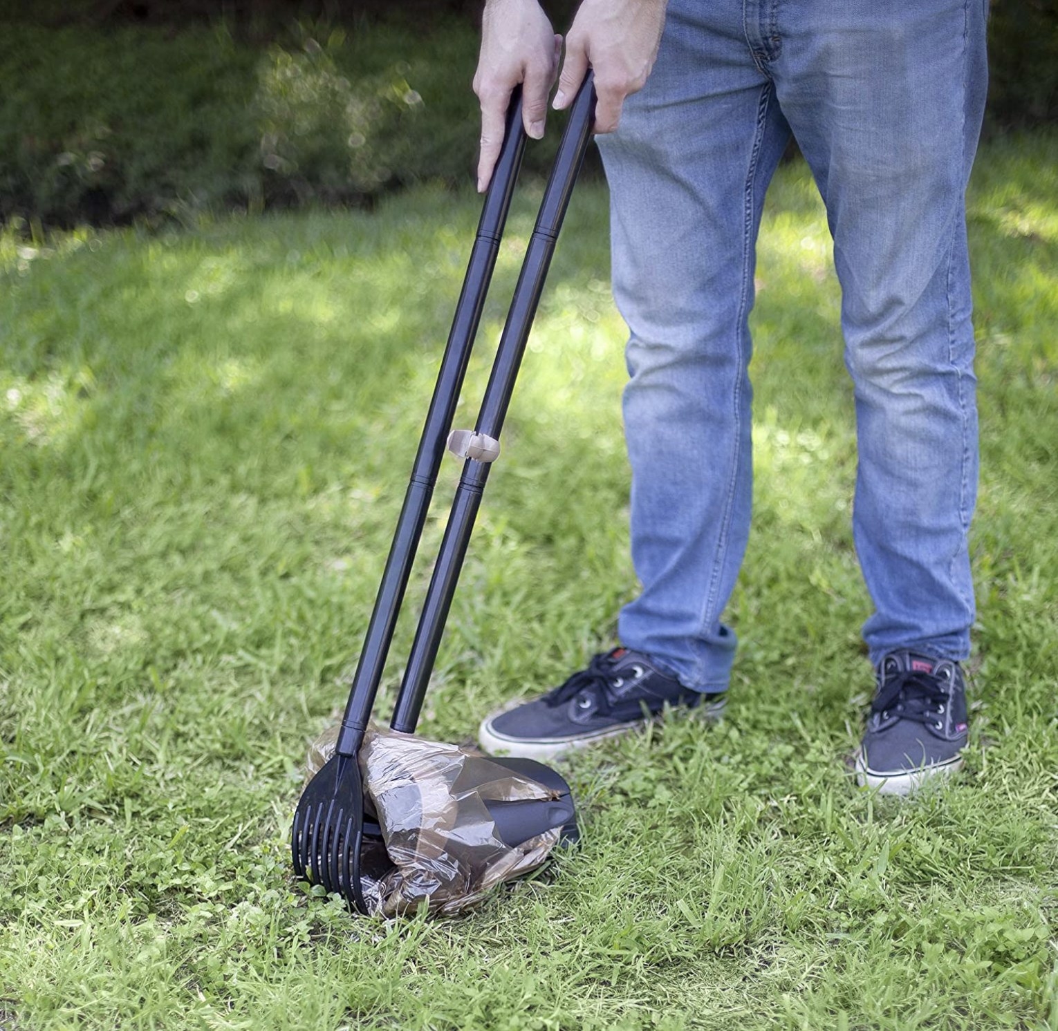 A person scooping from the grass into the bin