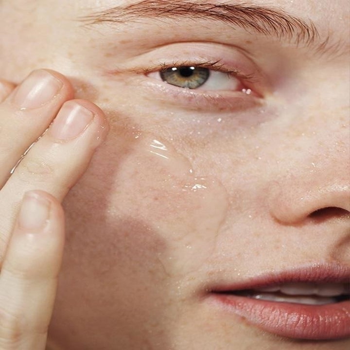 A person applying the cleanser to their face