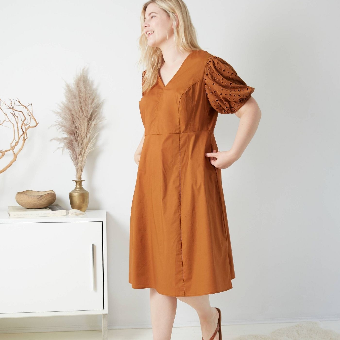 model wearing V-neck burnt orange dress with puffy sleeves