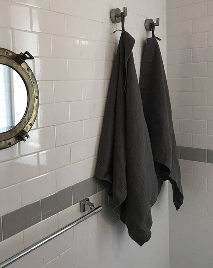 two dark grey linen bath sheets hangin on hooks