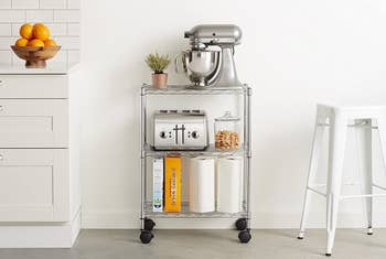 A three-shelf metallic room cart with wheels connected the bottommost