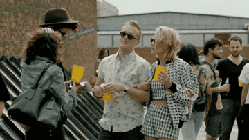 John Early and Meredith Hagner in &quot;search party&quot; waving happily at a rooftop party