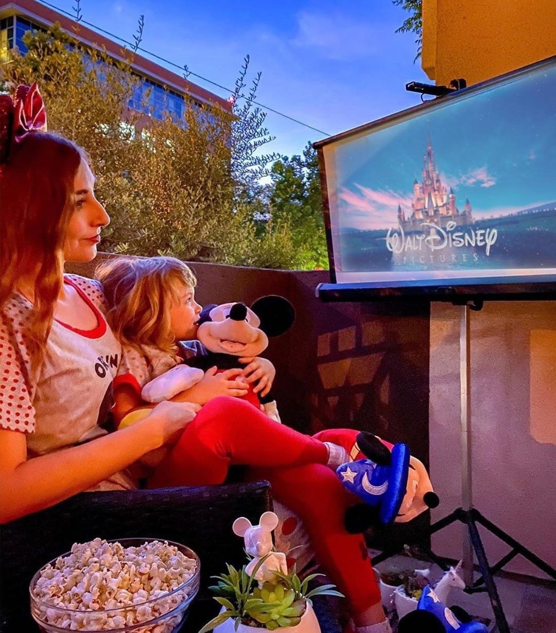 a mother and child watching a disney movie using the cinemood in their yard