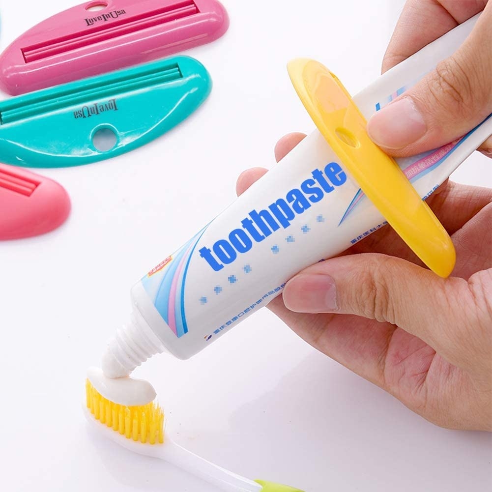 A person using the squeezer to put toothpaste on a brush