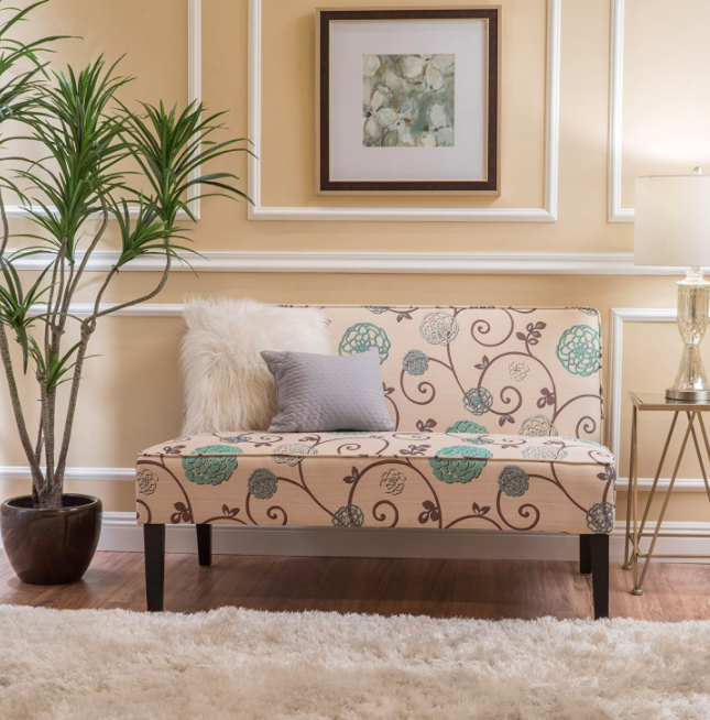 A pink green and blue floral-printed love seat in a living room