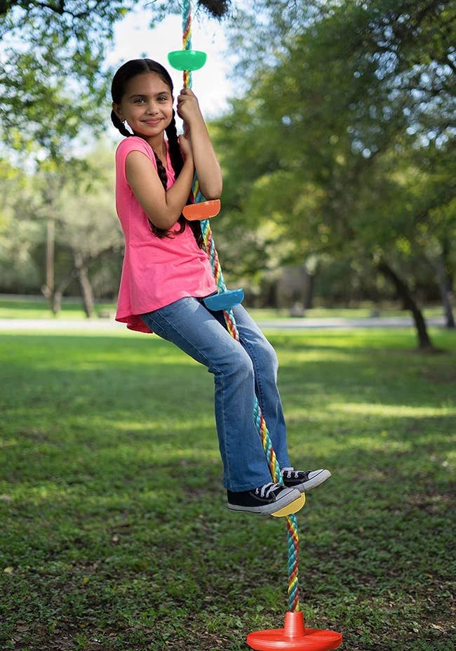 A child standing on the second wrung of the colorful rope