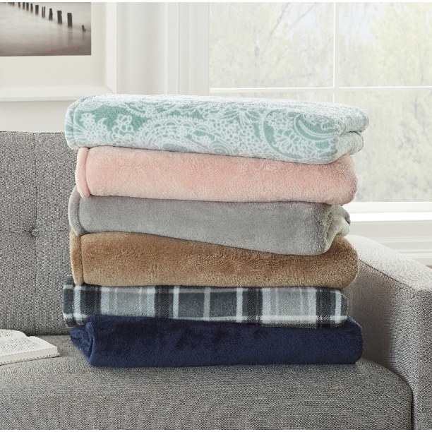 a stack of different colored plush blankets