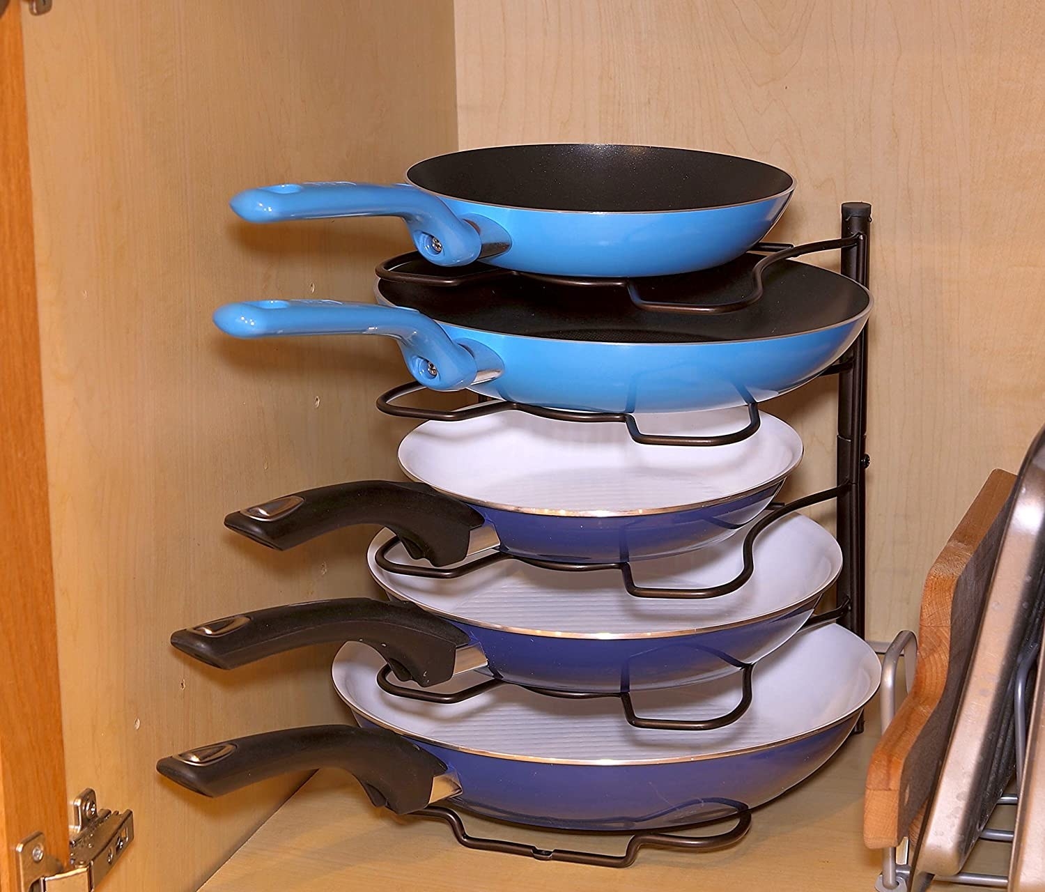 A rack holding up five different sizes pans in a cabinet 