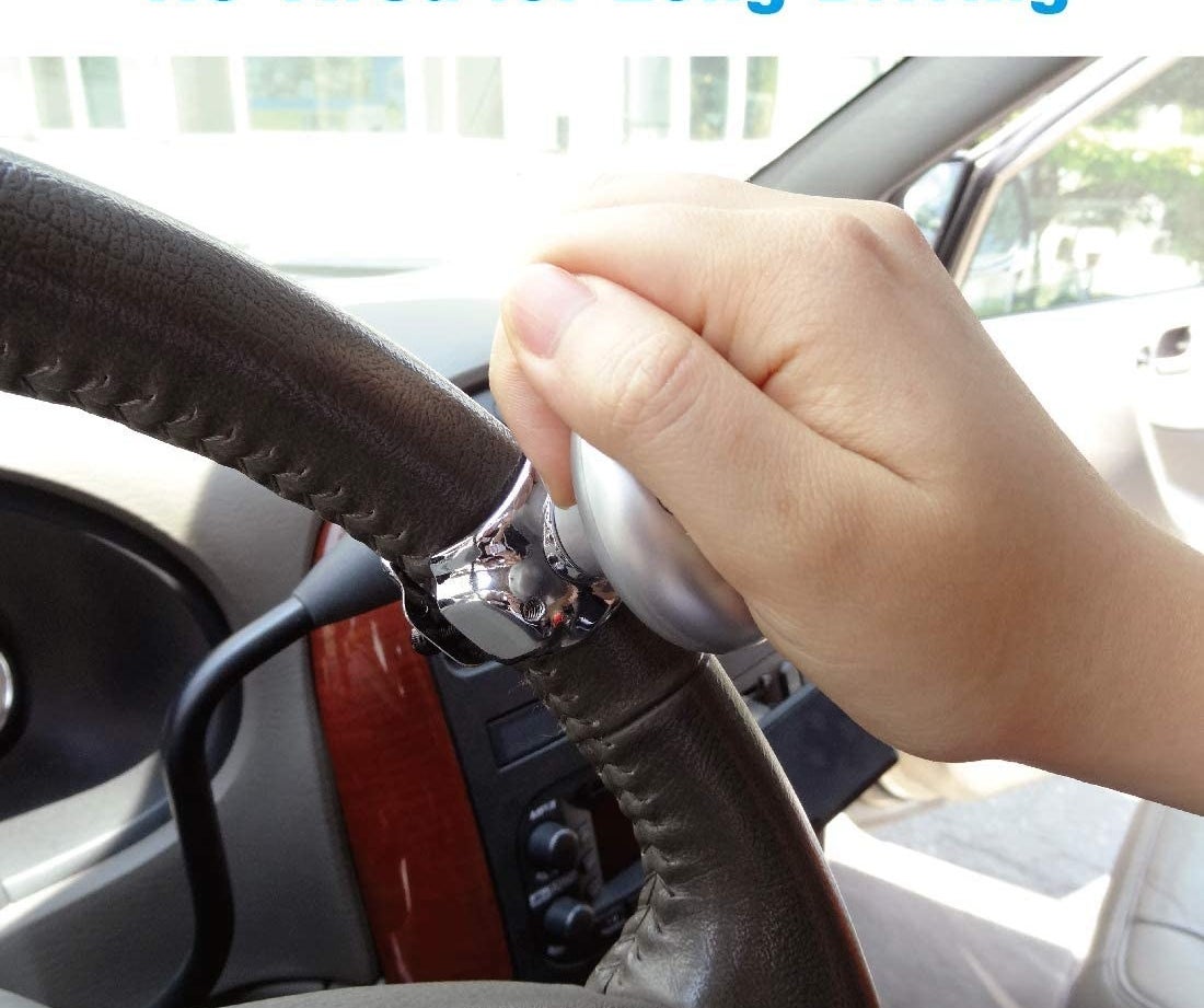view of steering wheel with person holding knob to control it