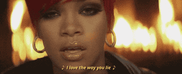 A GIF of a close-up of Rihanna singing &quot;I love the way you lie&quot; with a fire in the background from Eminem&#x27;s &quot;Love the way you lie&quot; video