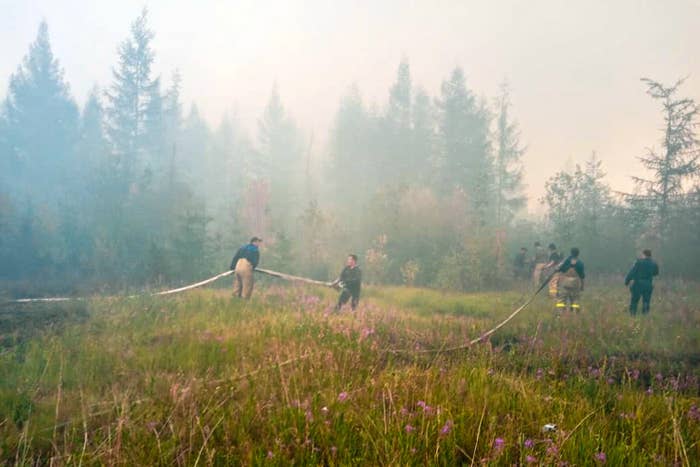 Firefighters carry hoses and extinguish fires near the village of Batagay, Sakha Republic, in Russia