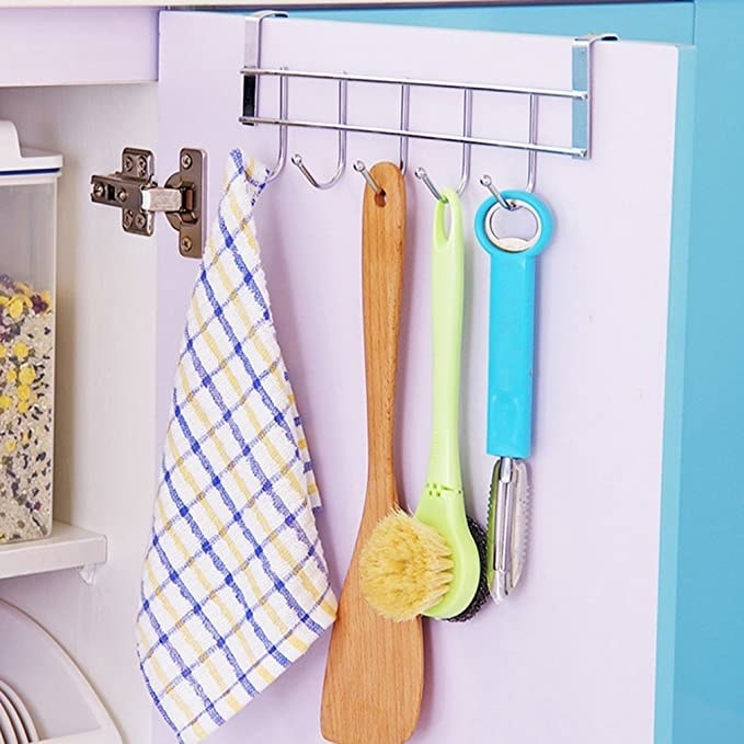 Towel, brush and peeler hanging off the shelf hooks.