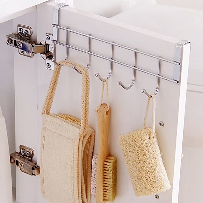 Steel kitchen hanger with brushes and kitchen towels hanging on it.