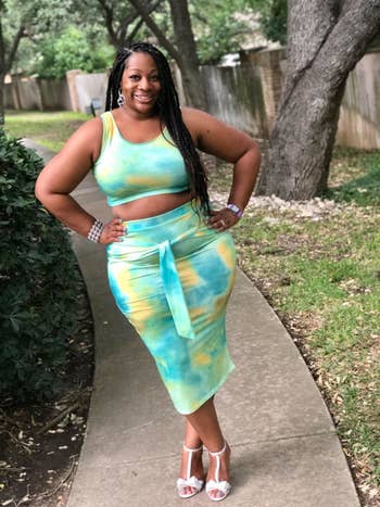 Reviewer wearing the crop tank top and bodycon midi skirt with a tie around the waist in green, blue, and yellow tie-dye 