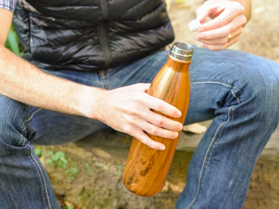 A person putting a Bottle Brite tablet into their water bottle