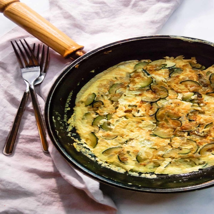 A frittata filled with zucchini and eggs in a skillet.
