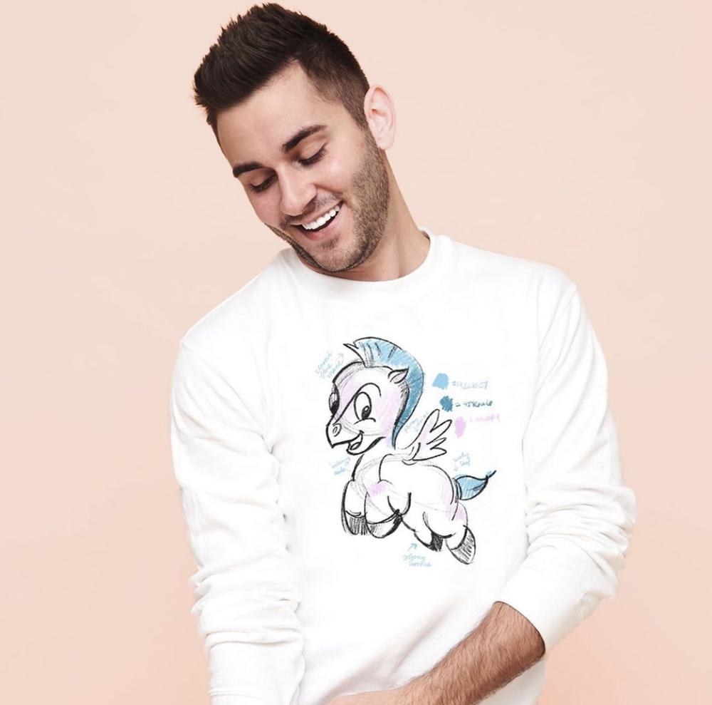 a model wearing a white sweatshirt with an illustrated drawing of baby pegasus on it