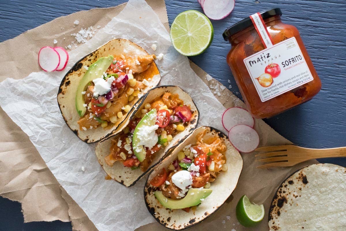 A jar of Matiz Sofrito on a table next to some tacos