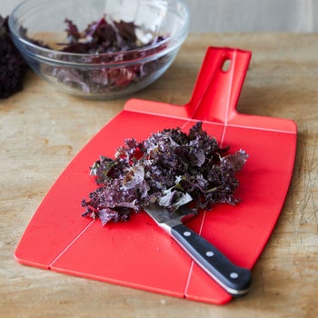 A still image shows the cutting board flat on a table with chopped vegetables on top