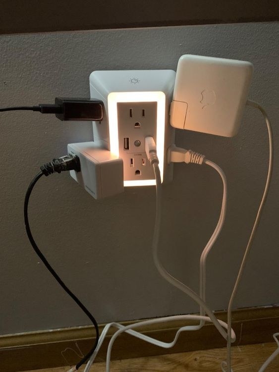 Reviewer&#x27;s picture of the light-up outlet with multiple large chargers attached 